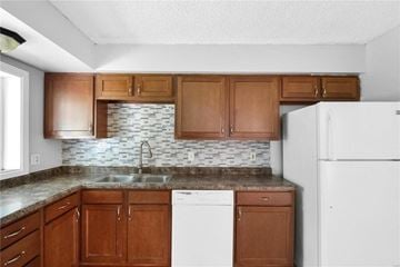 Florissant house for rent - a kitchen with wooden cabinets and a white refrigerator