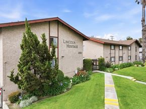 Anaheim apartment for rent - The Lincoln Heritage building is a two-story structure with a red roof and a green lawn in front.