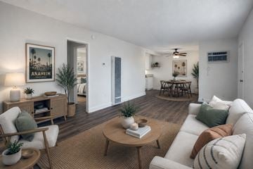 Anaheim apartment for rent - A living room with a white couch, a wooden coffee table, and a painting of Anaheim.
