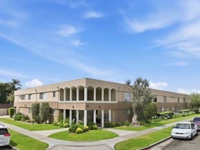 Anaheim apartment for rent - A building with a beige facade and a green lawn in front.