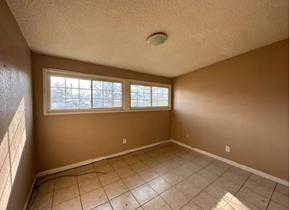 St Louis house for rent - an empty living room with a large window and a tiled floor