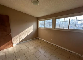 St Louis house for rent - an empty living room with three windows and a tiled floor