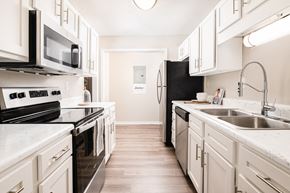 Walls apartment for rent - a kitchen with white cabinets and black appliances and a sink