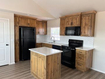 Shawnee house for rent - A kitchen with wooden cabinets and black appliances.