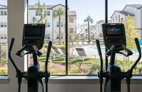 Houston apartment for rent - a gym with a view of a swimming pool and buildings