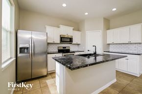 Lakeland house for rent - a kitchen with white cabinets and a black counter top