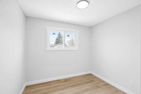 Calgary apartment for rent - a bedroom with white walls and a window and a hardwood floor