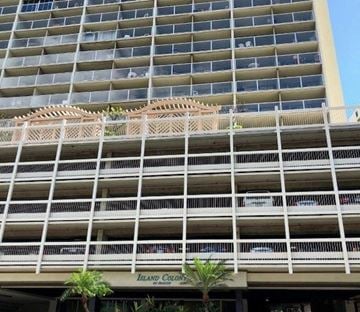 Honolulu apartment for rent - A large building with a balcony and a sign that says Island Colony.