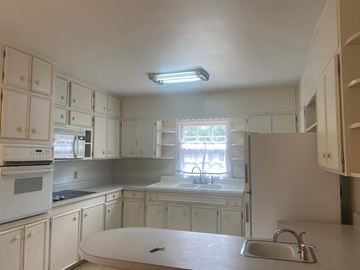 Greenwood house for rent - a kitchen with white cabinets and a sink and a window