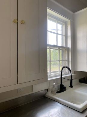 Greenwood house for rent - a kitchen with white cabinets and a sink and a window