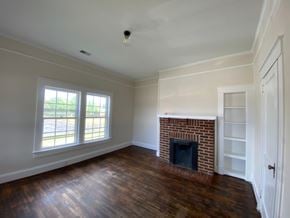 Greenwood house for rent - an empty living room with a brick fireplace and wooden floors