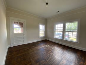 Greenwood house for rent - an empty living room with wooden floors and a white door
