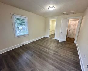 Greenville house for rent - an empty living room with hardwood floors and a window