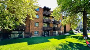 Calgary apartment for rent - A red brick building with a green lawn in front.