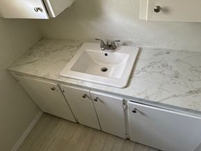 Newalla house for rent - A white sink with a marble countertop and a cabinet below it.