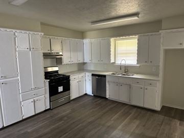 Newalla house for rent - A kitchen with white cabinets and a black stove top oven.