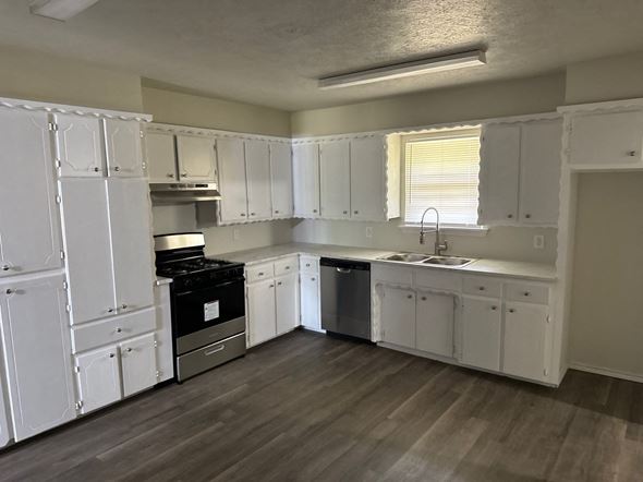 Newalla house for rent - A kitchen with white cabinets and a black stove top oven.