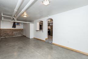 Denver apartment for rent - a living room with white walls and a concrete floor and an arched doorway