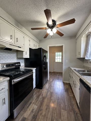 Clarksville house for rent - a kitchen with white cabinets and black appliances and a ceiling fan