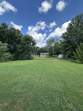 Clarksville house for rent - a large grassy field with trees and a house in the background