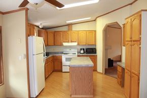 Trinidad house for rent - a kitchen with wooden cabinets and a white refrigerator