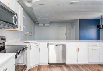 Louisville apartment for rent - a kitchen with white cabinets and stainless steel appliances and a blue wall