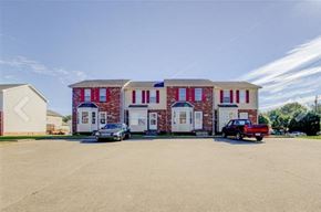 Oak Grove house for rent - A red brick building with white doors and windows is surrounded by a parking lot.
