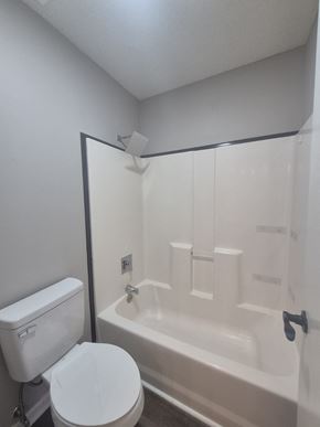 Oak Grove house for rent - A white toilet sits next to a white bathtub in a bathroom.