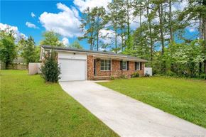 Fayetteville house for rent - a small brick house with a white garage door and a driveway