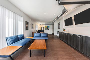 Detroit apartment for rent - A modern living room with a long wooden table and blue couches.