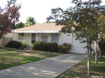Stockton house for rent - A white house with a brown roof and a tree in front.