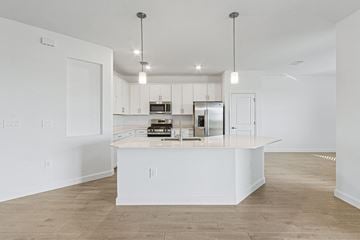 Estero house for rent - A kitchen with white cabinets and a white island with a microwave and oven on it.