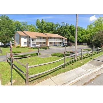 Rock Hill apartment for rent - A building with a brown roof is surrounded by a fence and greenery.