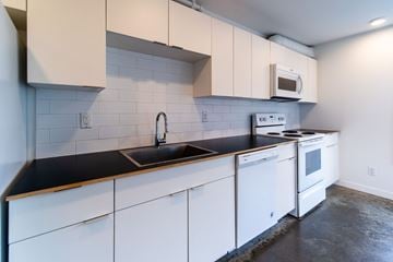 Victoria apartment for rent - A kitchen with white cabinets and a black countertop.