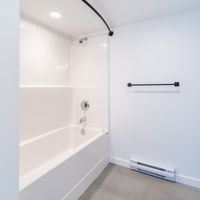Victoria apartment for rent - A white bathroom with a white tub and a white towel rack.