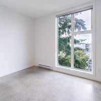 Victoria apartment for rent - A room with a large window and a view of trees outside.