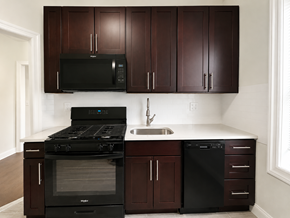 Bloomfield apartment for rent - A kitchen with dark brown cabinets and black appliances.