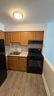 Bayonne apartment for rent - A kitchen with wooden cabinets and black appliances.