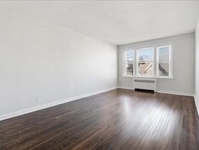 Hasbrouck Heights apartment for rent - A room with wooden floors and a window showing a view of other houses.