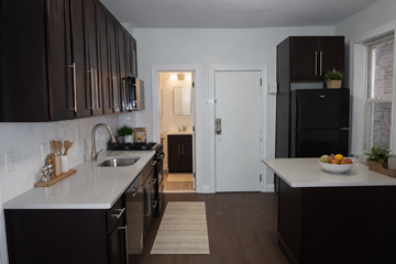 Bayonne apartment for rent - A kitchen with dark brown cabinets and a white counter top.