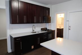 Bayonne apartment for rent - A kitchen with dark brown cabinets and white countertops.