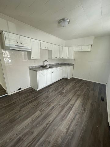 Lima apartment for rent - A kitchen with white cabinets and a wooden floor.