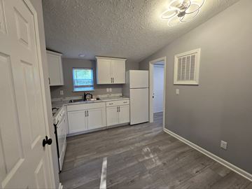 Gary house for rent - a kitchen with white cabinets and a sink and a refrigerator