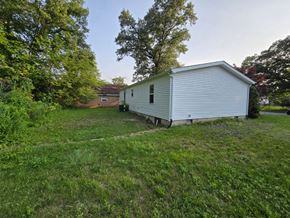Gary house for rent - a mobile home sits in a grassy yard with a house in the background