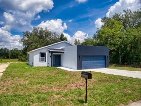 Ocklawaha house for rent - A modern house with a grey exterior and a blue garage door.