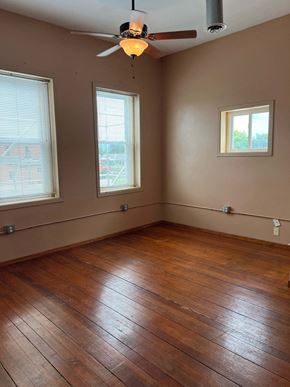Grinnell apartment for rent - an empty living room with wooden floors and a ceiling fan