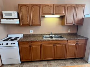 Grinnell apartment for rent - a kitchen with a sink and stove and wooden cabinets