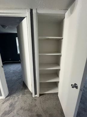 Cleveland apartment for rent - A white closet with shelves is open to a room with a black wall.