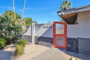 Palm Desert apartment for rent - a red door on a building with a fence and palm trees