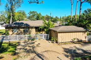 Sarasota house for rent - a house with a garage and a yard with a fence